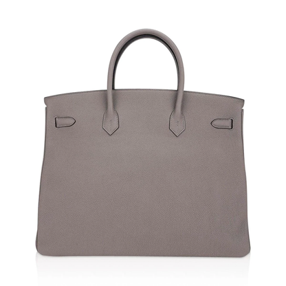 Muted Ash Gray Pebble Grain Large Trapezoid Hand Tote With Warm Polished Golden Twist Lock Hardware And Matching Suspended Engraved Metal Padlock Charm